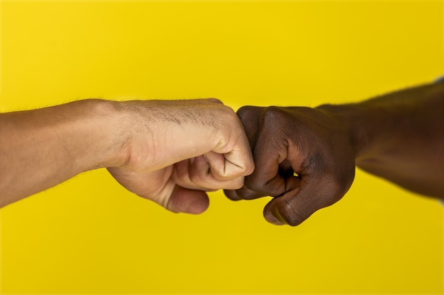 Free photo foreground european and afroamerican hand to hand clenched into fists