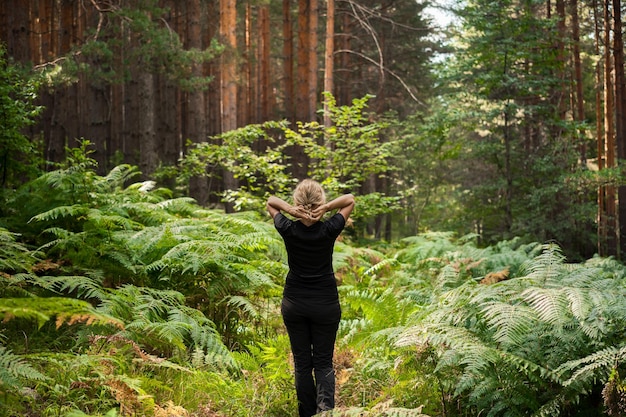 Foto gratuita bagni nel bosco ripristino della forza e della psiche una donna adulta cammina lungo un sentiero nel bosco tra le felci