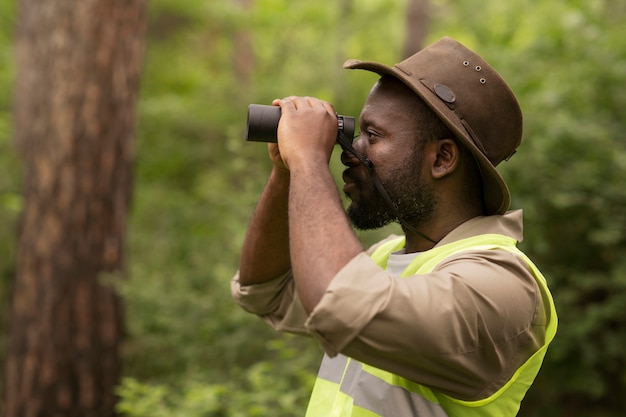 Forest warden using binoculars side view