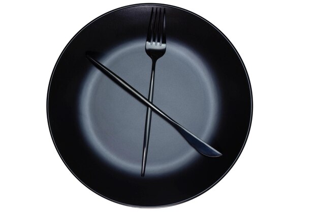 Fork and knife on black plate, representing a clock. white background.