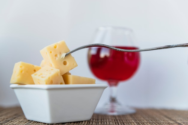 Fork near set of fresh cheese in saucer and glass of drink