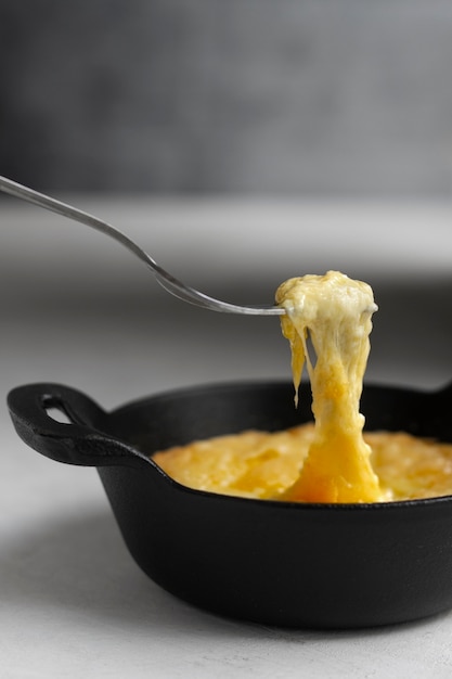 Free photo fork picking up melted cheese from bowl