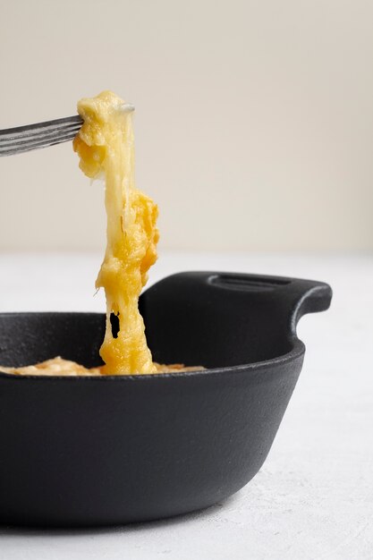 Fork picking up melted cheese from bowl