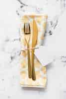 Free photo fork; table knife and napkin tied with blank white tag and string on marble textured background