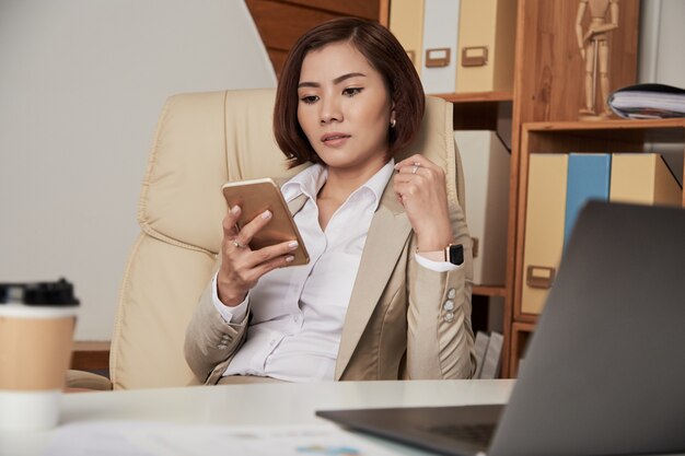 Formal businesswoman using phone in office