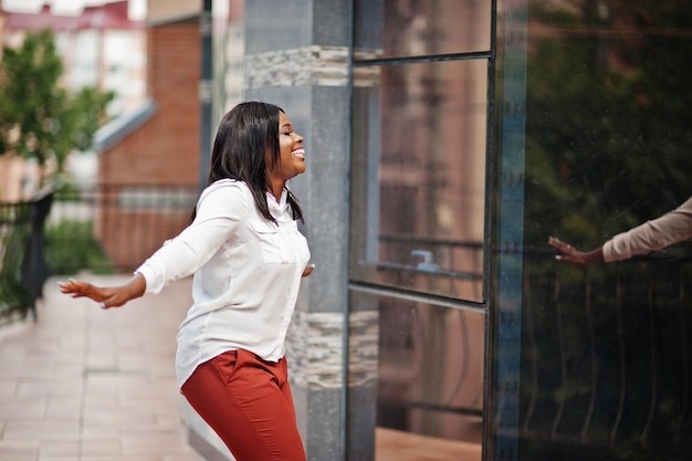 Formally dressed african american business woman in white blouse and red trousers Successful dark skinned businesswoman