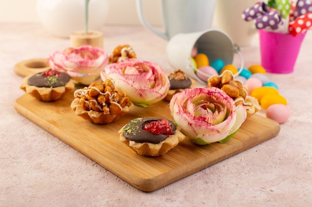 A fornt view little chooclate cakes with flower and colorful candies