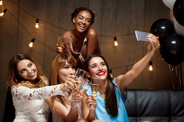 Four beautiful girls making selfie at party.