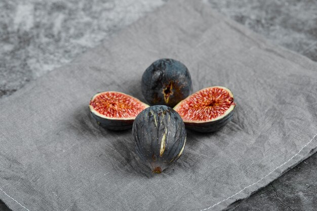 Four black figs on a marble background with a grey tablecloth. High quality photo