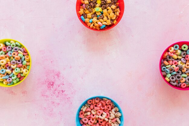 Four bowls with cereals on pink table