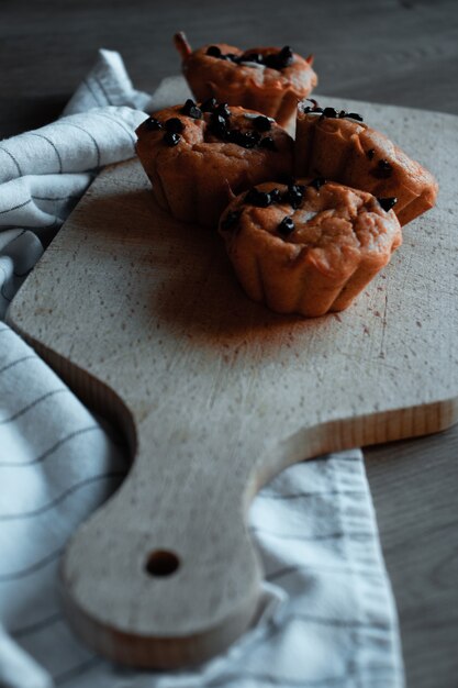 Four brown cupcakes on brown wooden chopping board