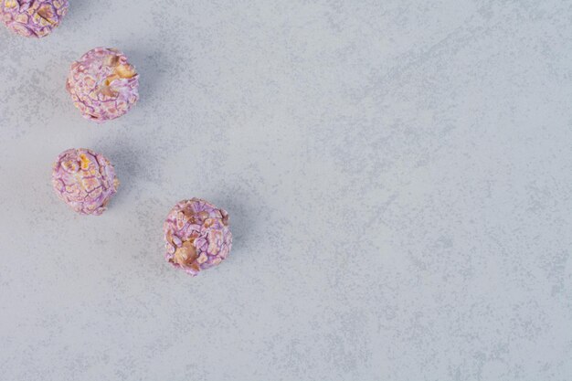 Four candied popcorns lined up on marble surface