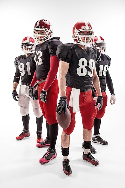 The four caucasian fitness men as american football players posing  full-length with a ball on white background
