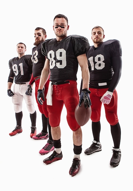 Free photo the four caucasian fitness men as american football players posing  full-length with a ball on white