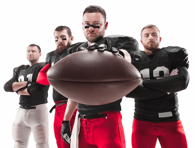 The four caucasian fitness men as american football players posing  full-length with a ball on white
