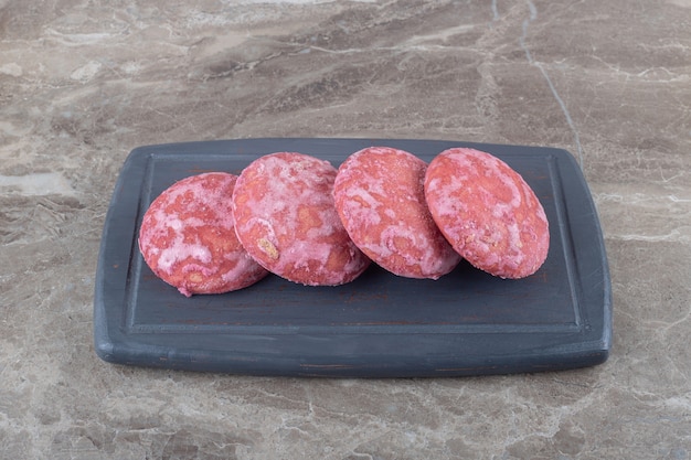 Four cookies on a navy board on marble surface