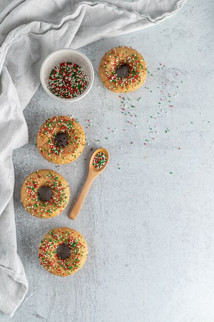Four donuts with sprinkles on top near brown wooden spatula