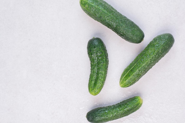 Free photo four fresh cucumbers on white table.