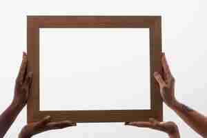 Free photo four hands holding big wooden frame
