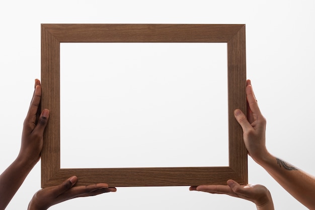 Four hands holding big wooden frame