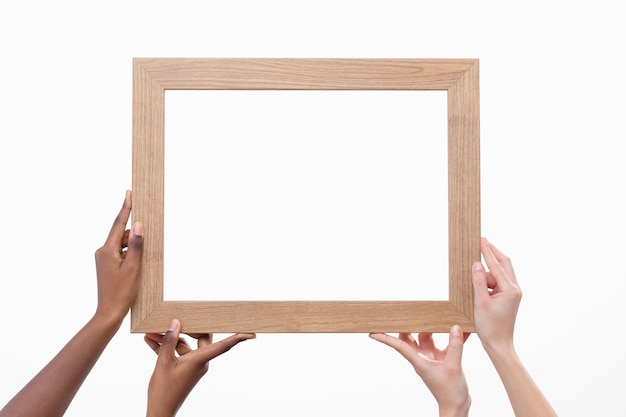 Free photo four hands holding wooden frame front view