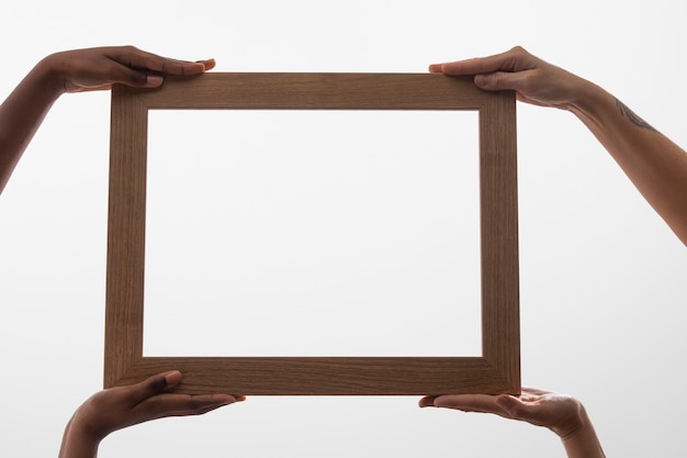 Free photo four hands holding wooden frame