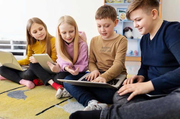 Foto gratuita quattro ragazzi che lavorano insieme usando i loro laptop e tablet