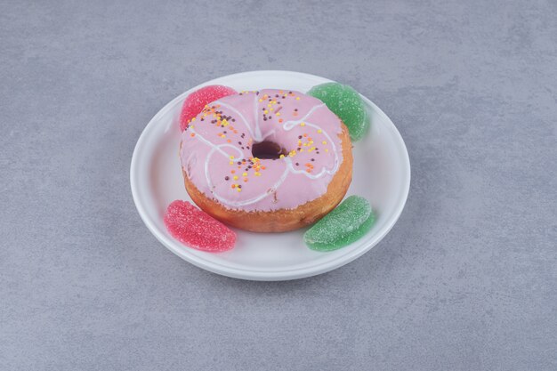 Four marmelades and a donut on a platter on marble surface