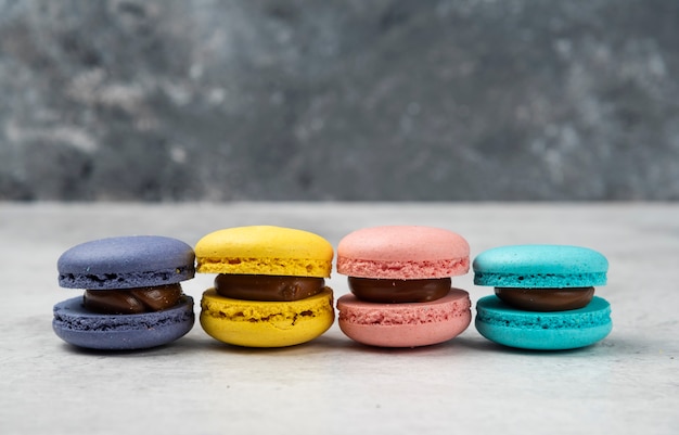 Four multicolored macarons dessert on white table. 