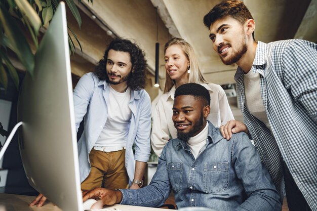 Four multiethnic colleagues looking at computer screen in office