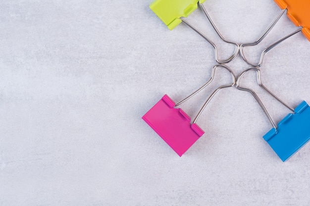 Four paper clips on white surface.