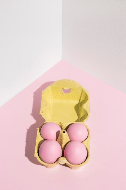 Four pink Easter eggs in yellow rack on table