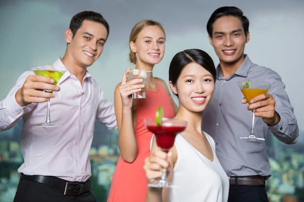 Four Smiling People with Cocktails Toasting in Bar