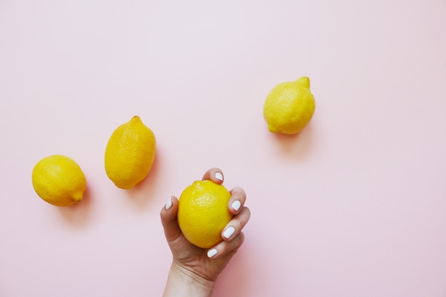 Quattro limoni gialli su uno sfondo rosa