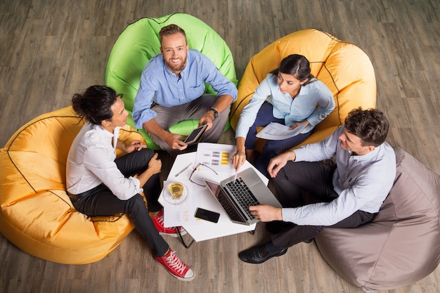 Quattro giovani colleghi che lavorano su sedie beanbag