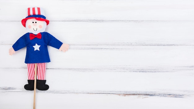 Free photo fourth of july traditional flag doll on white wooden surface