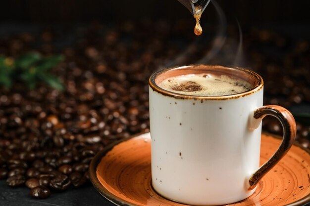 黒いテーブルの上の香りのよいエスプレッソポットから一滴のコーヒーがカップに落ちる