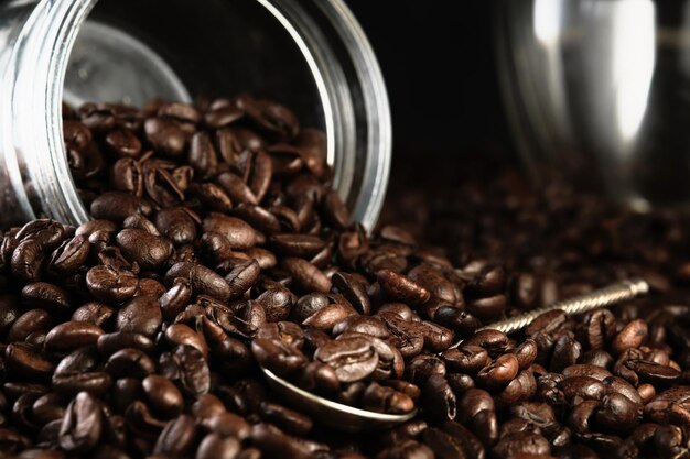 Fragrant freshly roasted coffee beans are scattered from the jar onto the countertop Copy space banner Closeup selective focus