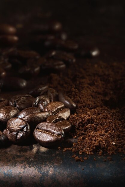 Free photo fragrant freshly roasted coffee beans and ground coffee are scattered on a metal tray closeup selective focus vertical frame