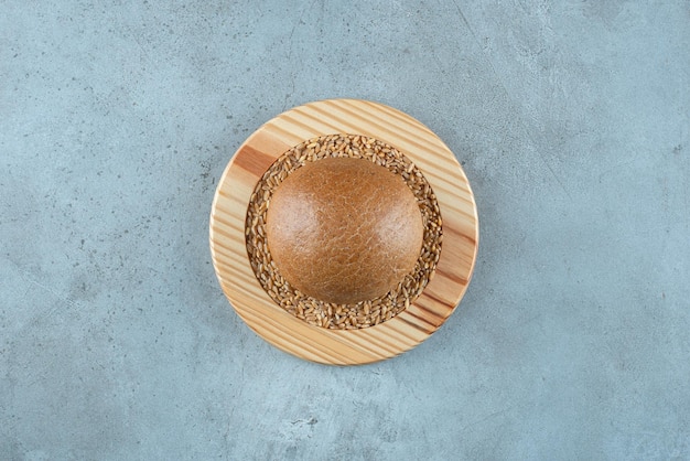 Free photo fragrant rye bun on wooden plate with barley.