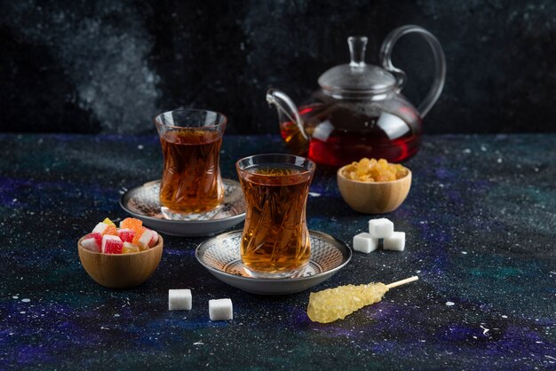 Fragrant tea with candies on blue surface