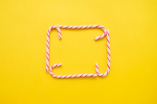 frame of candy canes on yellow background