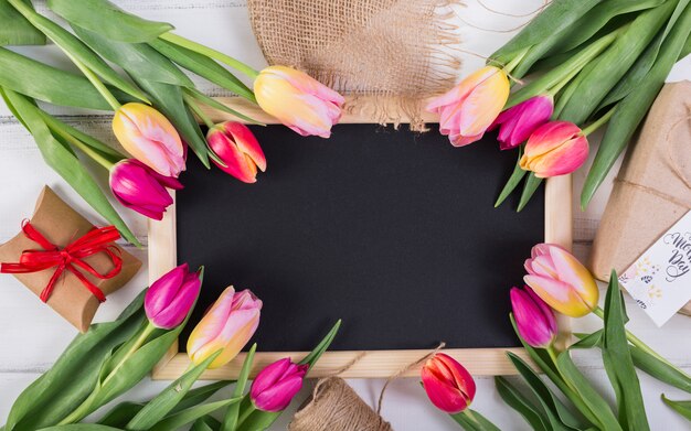 Рамка классной доски украшена тюльпанами и подарочными коробками