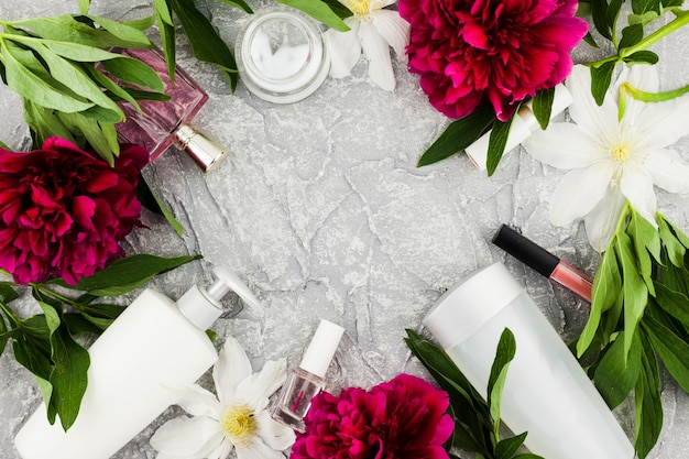 Foto gratuita cornice di cosmetici e profumi con fiori