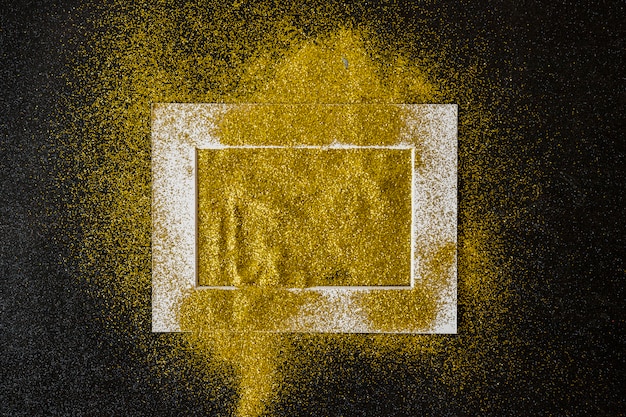 Бесплатное фото Рамка, покрытая желтыми блестками на столе