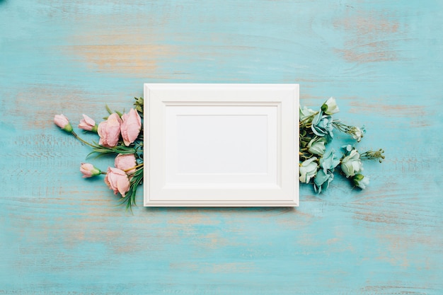 Free photo frame and flowers on blue wooden background.