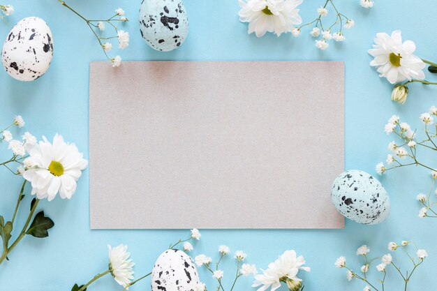 Рамка из цветов с листом бумаги и яйцами
