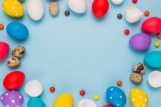 Frame from Easter eggs and candies on blue table