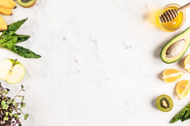 Frame of ingredients for a green smoothie of vegetables and fruits or for a fresh salad on a white background, top view, copy space.