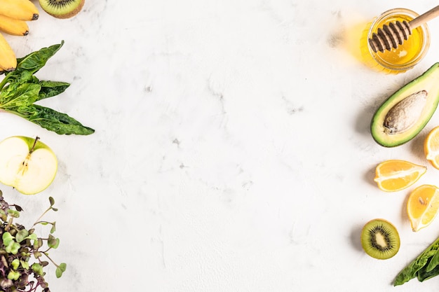 Frame of ingredients for a green smoothie of vegetables and fruits or for a fresh salad on a white background, top view, copy space.